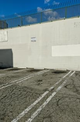 A parking lot bakes in the sun and cracks have risen up as the concrete breaks under pressure.